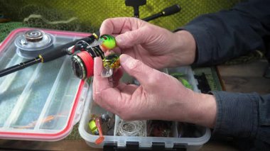 Yaşlı bir balıkçı balıkçı olta takımlarını toplayıp ekipmanları kontrol ediyor. Ellerine yakın çekim..