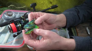 Yaşlı bir balıkçı balıkçı olta takımlarını toplayıp ekipmanları kontrol ediyor. Ellerine yakın çekim..