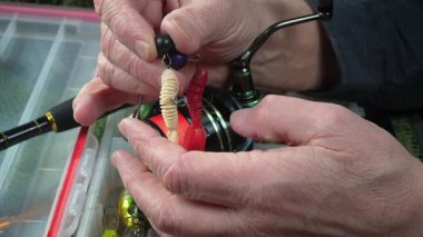 Yaşlı bir balıkçı balıkçı olta takımlarını toplayıp ekipmanları kontrol ediyor. Ellerine yakın çekim..