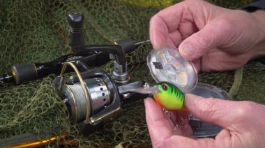 Yaşlı bir balıkçı balıkçı olta takımlarını toplayıp ekipmanları kontrol ediyor. Ellerine yakın çekim..