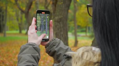 Genç, güzel bir kız doğada seyahat eder, sonbahar ormanının güzelliğine hayranlıkla hayran kalır, fotoğraf çeker, defterine notlar yazar, gülümser, eğlenir. Yavaş çekim.