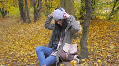 Genç, güzel bir kız doğada seyahat eder, sonbahar ormanının güzelliğine hayranlıkla hayran kalır, fotoğraf çeker, defterine notlar yazar, gülümser, eğlenir. Yavaş çekim.