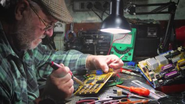 Atölyedeki ana kartı tamir et. Ustanın elleri, kullanım sürecindeki arızalar nedeniyle elektronik aletleri tamir edecek şekilde yakın plan çekimde. Yakın plan. Yavaş çekim.