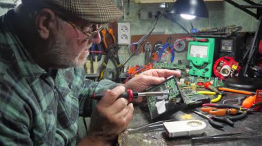 Atölyedeki ana kartı tamir et. Ustanın elleri, kullanım sürecindeki arızalar nedeniyle elektronik aletleri tamir edecek şekilde yakın plan çekimde. Yakın plan. Yavaş çekim.