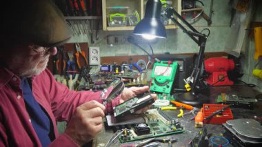 Atölyedeki ana kartı tamir et. Ustanın elleri, kullanım sürecindeki arızalar nedeniyle elektronik aletleri tamir edecek şekilde yakın plan çekimde. Yakın plan. Yavaş çekim.