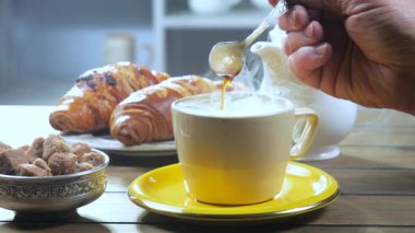 Yaşlı bir adamın elleri yavaşça sıcak espresso kahvesini kaşıkla karıştırıyor. Yavaş çekim.