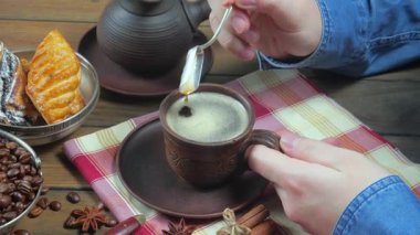 Genç bir adam kaşıkla kahve karıştırıyor..