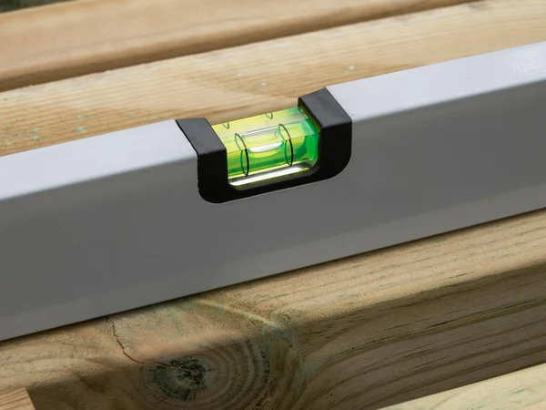 Spirit level or construction water level checking the level of a plank of wood. Close up image.