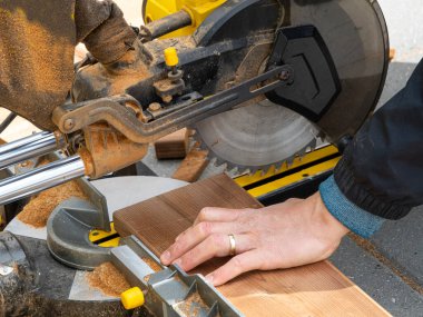 Dairesel bıçakla çalışan bir adam odun kesmek için testere kullanıyor. El gücü araçlarının resmini kapat.