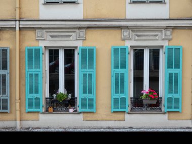 Fransa güzel, balkon kutularında çiçekler ve panjurlar olan renkli bir cephe..