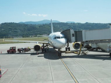 Jet köprüsü üzerinden havaalanı terminaline bağlı yolcu bindirme köprüsü olan havaalanında bir uçak. Bilbao, İspanya - 14 Temmuz. 2023.