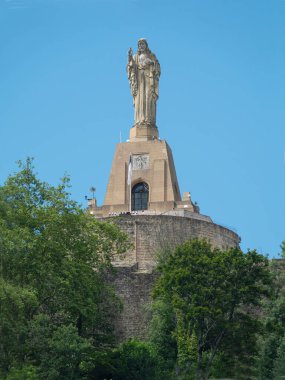 San Sebastian 'da İsa heykeli. Urgull Tepesi 'nin tepesinde San Sebastian' a tepeden bakan bu Kutsal Yürek İsa heykeli var. Mavi gökyüzü arkaplanı.