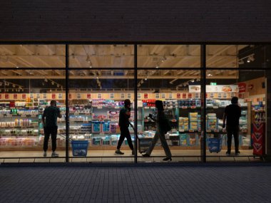 Geceleri süpermarketin penceresinden bakmak. İnsanlar alışverişe gider. 