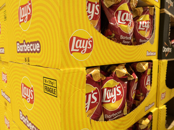 Lay's potato chips for sale in grocery store. The chip bags are in a large carton box. Copenhagen, Denmark - September 3, 2023.