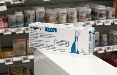 Packaging box of Wegovy (semaglutide) injectable prescription medication, weight-loss drug from Novo Nordisk AS. Pharmacy shop shelves in background. Copenhagen, Denmark - November 13, 2023. clipart