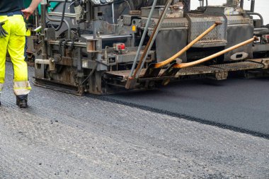 Asfalt yol yüzeyinin tamiri - eski katman kaldırıldı ve inşaat sahasına yeni asfalt döşeyen endüstriyel kaldırım kamyonu.
