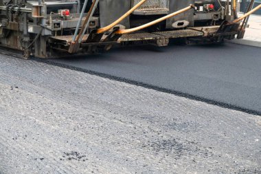 Asfalt yol yüzeyinin tamiri - eski katman kaldırıldı ve inşaat sahasına yeni asfalt döşeyen endüstriyel kaldırım kamyonu.