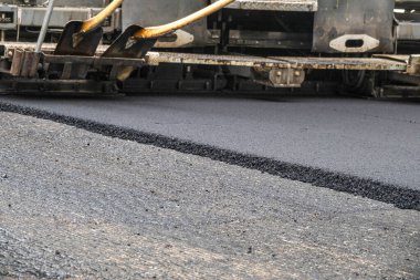 Asfalt yol yüzeyinin tamiri - eski katman kaldırıldı ve inşaat sahasına yeni asfalt döşeyen endüstriyel kaldırım kamyonu.