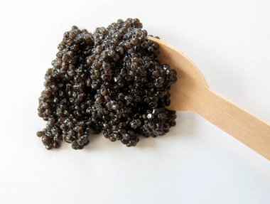 Beyaz arka planda kaşık olan siyah havyar. Üst Manzara. Gurme deniz ürünleri lezzeti..