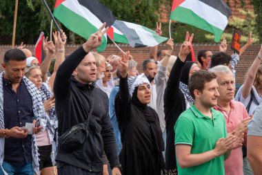 Filistin 'le dayanışmalarını ve Filistin bayraklarıyla el sallamalarını göstermek için gösteri yapan bir grup insan. Zafer işareti için V 'yi elleriyle gösteriyor, Kopenhag, Danimarka - 27 Temmuz 2024.