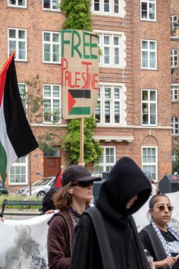 Filistin 'le dayanışmalarını ve Filistin bayraklarıyla el sallamalarını göstermek için gösteri yapan bir grup insan. Ve bir poster göstererek. Kopenhag, Danimarka - 27 Temmuz 2024.