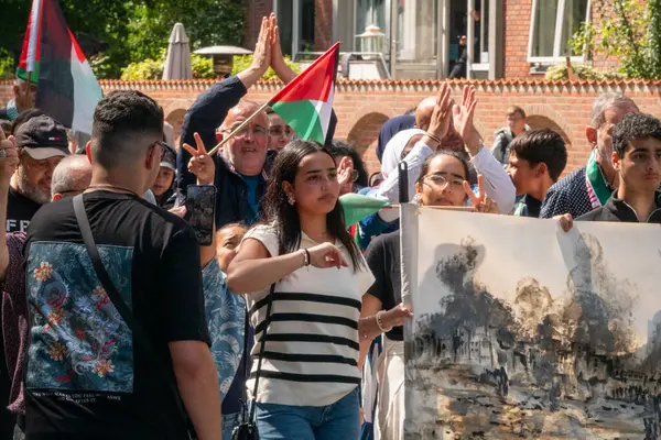 stock image Crowd of people marching in demonstration to express their solidarity with Palestine and waving with palestinian flags. Copenhagen, Denmark - July 27, 2024.