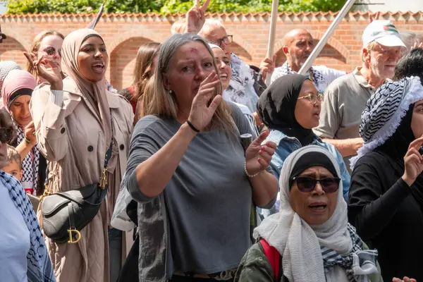 stock image Crowd of people marching in demonstration to express their solidarity with Palestine and waving with palestinian flags. Arab woman in front. Copenhagen, Denmark - July 27, 2024.