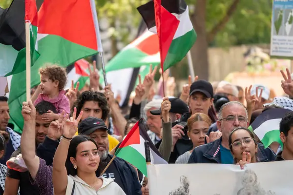 stock image Crowd of people marching in demonstration to express their solidarity with Palestine and waving with palestinian flags. Copenhagen, Denmark - July 27, 2024.