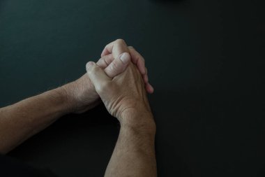 İnce kollu erkek elleri katlanmış ellerle dua ederken parmakları birbirine dolanmış karanlık sahnelerde fotokopi çekiliyor. Dini kavram.