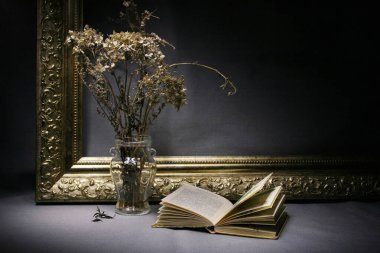 Altın çerçevenin arka planında kurutulmuş ortanca ve yanında küçük bir kitap bulunan bir buket var. Metin için boşluk var.
