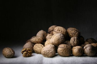 Birçok soyulmamış ceviz bir yığın halinde kumaşla kaplı bir masanın üzerinde duruyor.