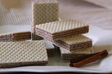 Tarçın çubuğuyla süslenmiş bir tabakta çikolata katmanı olan çok katmanlı beyaz kurabiyeler. 