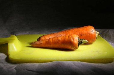 İki soyulmamış havuç kesme tahtasının üzerinde duruyor.