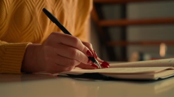 詳細認識不能な女性の書き込みノートや机の指にショッピングリストのノートブック赤いポリッシュネイルを保持 — ストック動画
