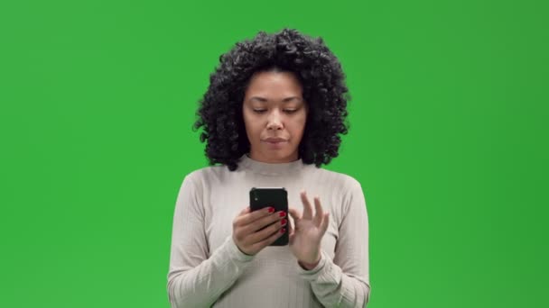 アフリカ系アメリカ人女性がスマートフォンのスクロール写真を持っています日付アプリ緑の画面に隔離 — ストック動画