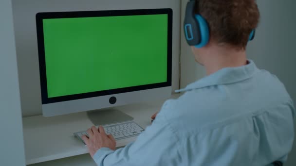 Человек Наушниками Сидит Столом Играет Онлайн Игру Компьютере Зеленым Экраном — стоковое видео