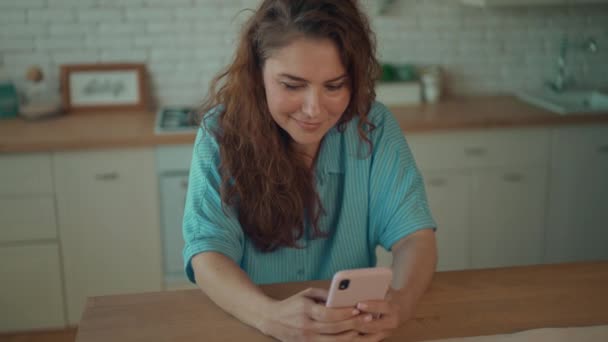 Szczęśliwa Uśmiechnięta Kobieta Stojąca Przy Stole Kuchennym Trzymając Smartfona Czacie — Wideo stockowe