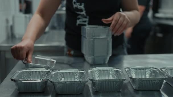 閉じられた女性はチャリティキッチンのボランティア活動に弁当箱を置いて — ストック動画