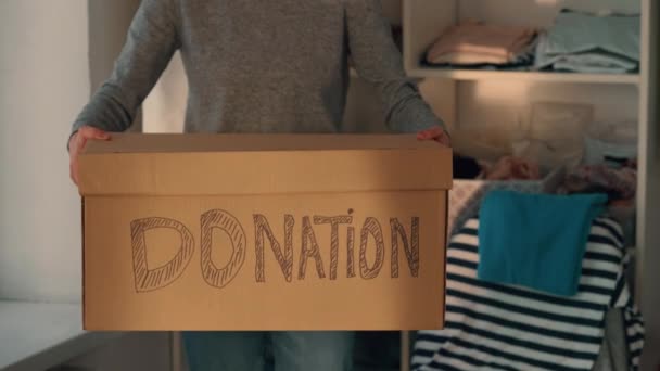 向摄像盒展示慈善团体捐赠物品的服装的人 — 图库视频影像