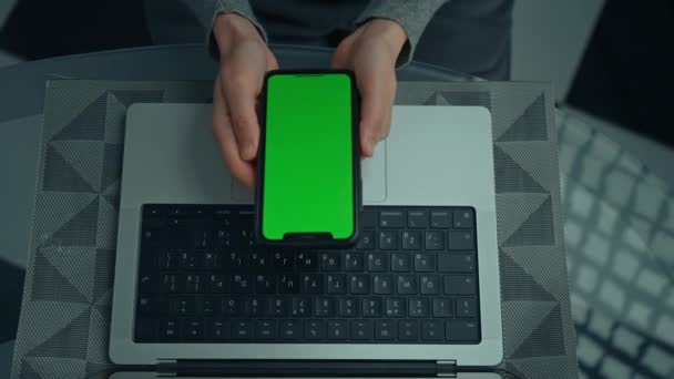 桌上拿着装有绿色屏幕笔记本电脑的智能手机的女人 — 图库视频影像