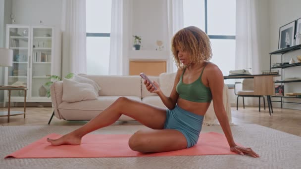 Frau Aktivkleidung Sitzt Auf Yogamatte Und Hält Smartphone Sport Teilen — Stockvideo