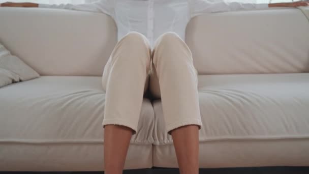 Жінка Сидить Дивані Ноги Акуратно Схрещені Вона Здається Розслабленою Зосередженою — стокове відео