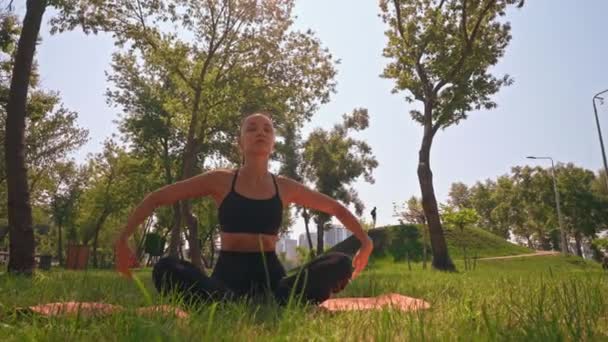 Een Vrouw Zit Een Yoga Positie Een Park Concentreert Zich — Stockvideo