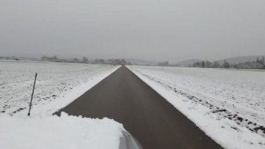 Kışın karlı tarlalar ve ıslak kır yolu