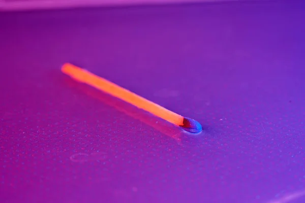 close up of a match on a pink background