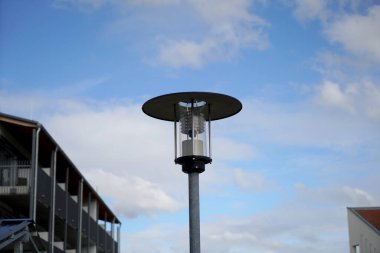 a low angle shot of a lamppost with the roof of a modern building