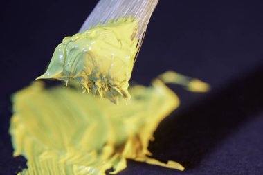close up of a yellow and white paint on a black background