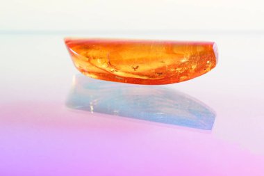 Amber gemstone on pink and blue background. Shallow depth of field                               