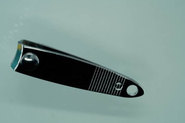 Close up of a nail clipper on a gray background with copy space