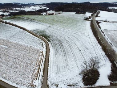 Drone shot of snowy agricultural snowy fields in Bavaria on a cloudy day